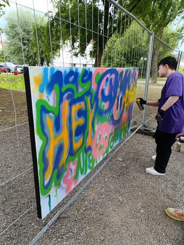 Plakat wird mit Farbe besprüht