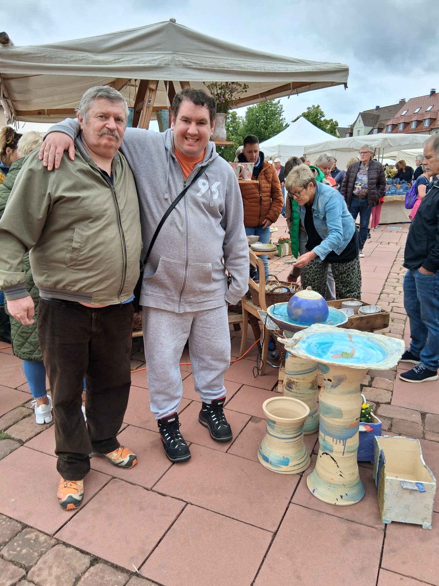 Bewohner an einem Stand des Töpfermarktes