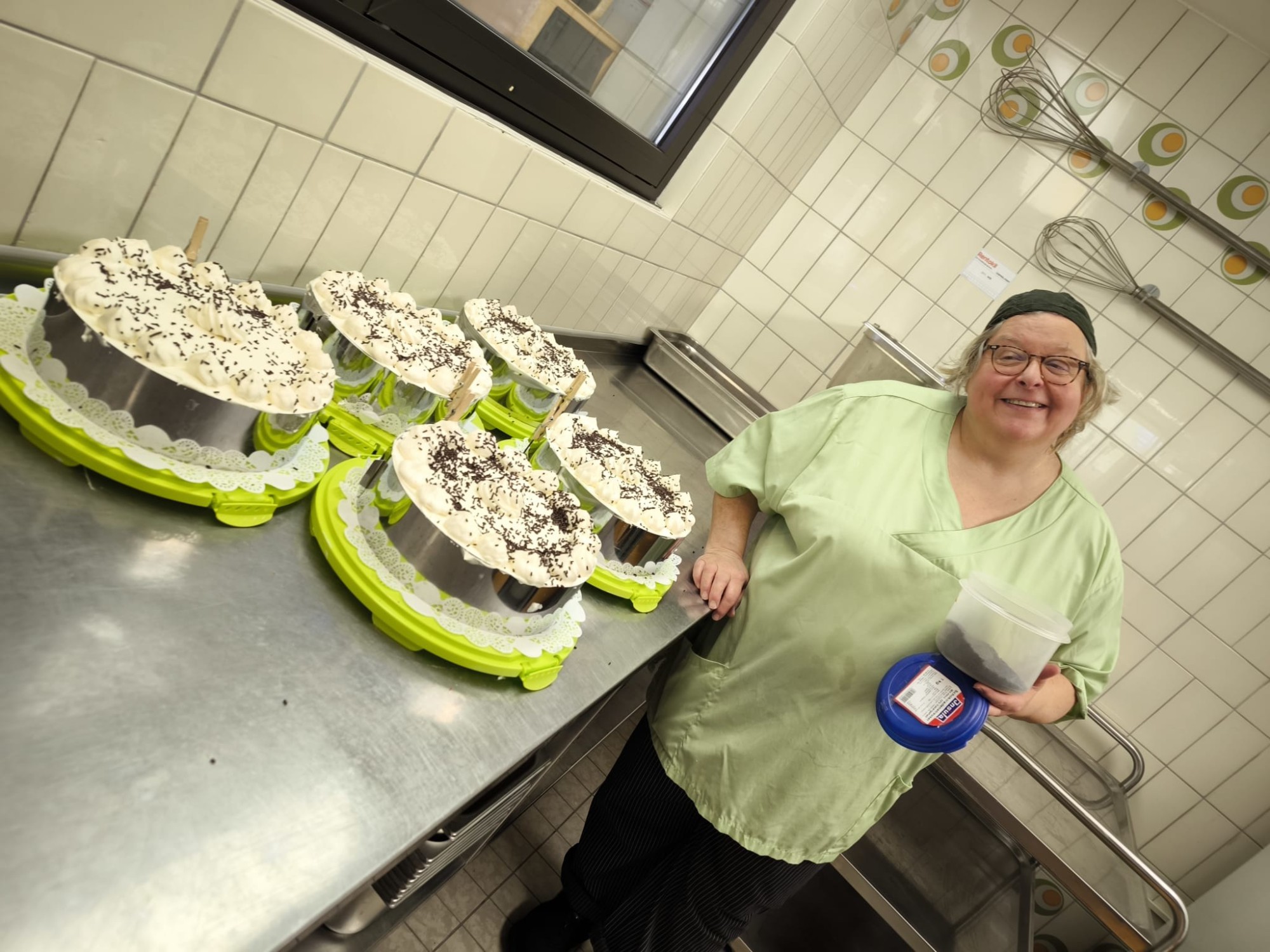 Mitarbeiterin pr&auml;sentiert selbstgebackene Torten